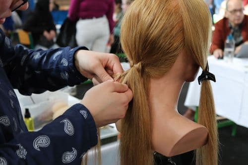 Fodrász tanuló hajat fon egy próbababán